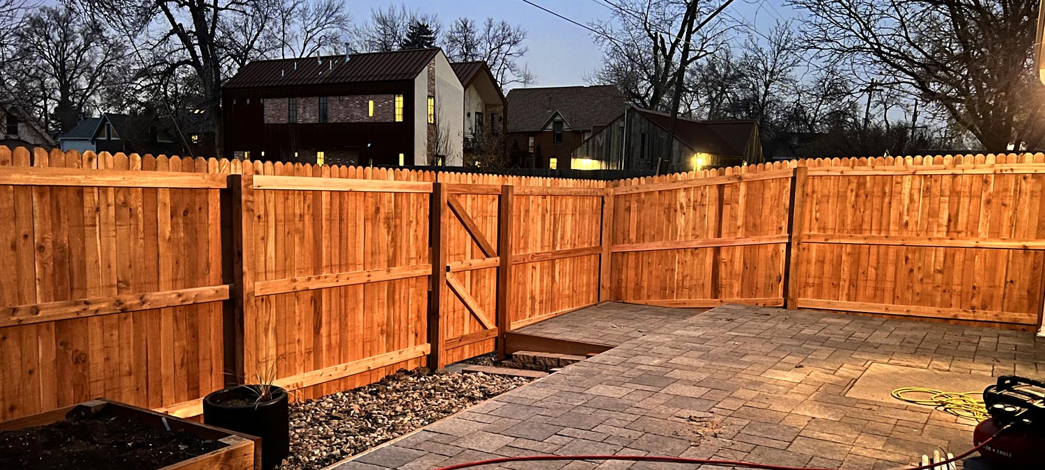 Cedar wood dog ear picket fence along alley at dusk, in Wheat Ridge, Denver, Colorado.