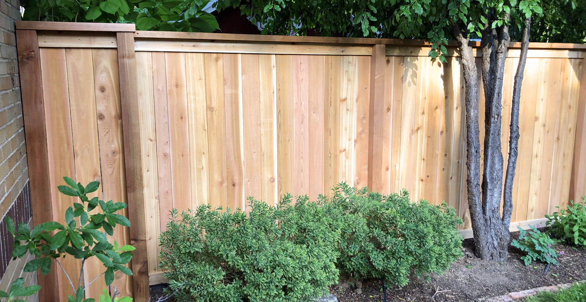 Detail of cedar wood picket fence with top cap and trim board in Congress Park neighborhood in Denver, Colorado.